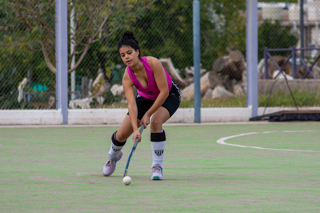 Dynamic shot of a female field hockey player in action outdoors on a green field.