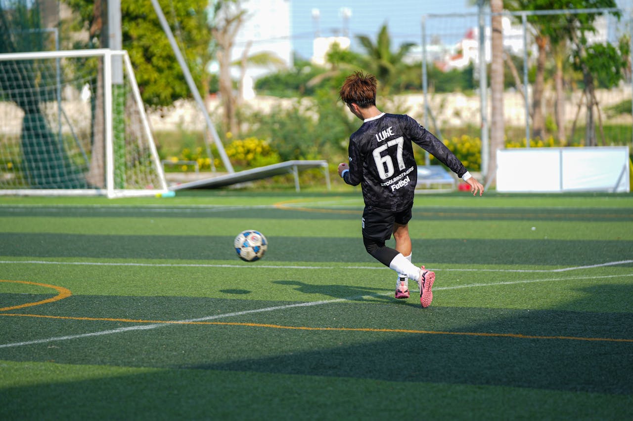 Captured moment of a young soccer player kicking the ball on a sunny outdoor field.