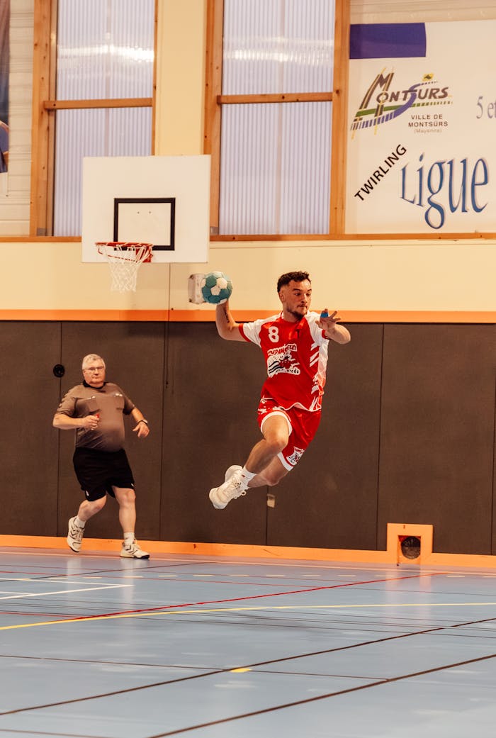 Action shot of a handball player jumping in an indoor sports arena in France.